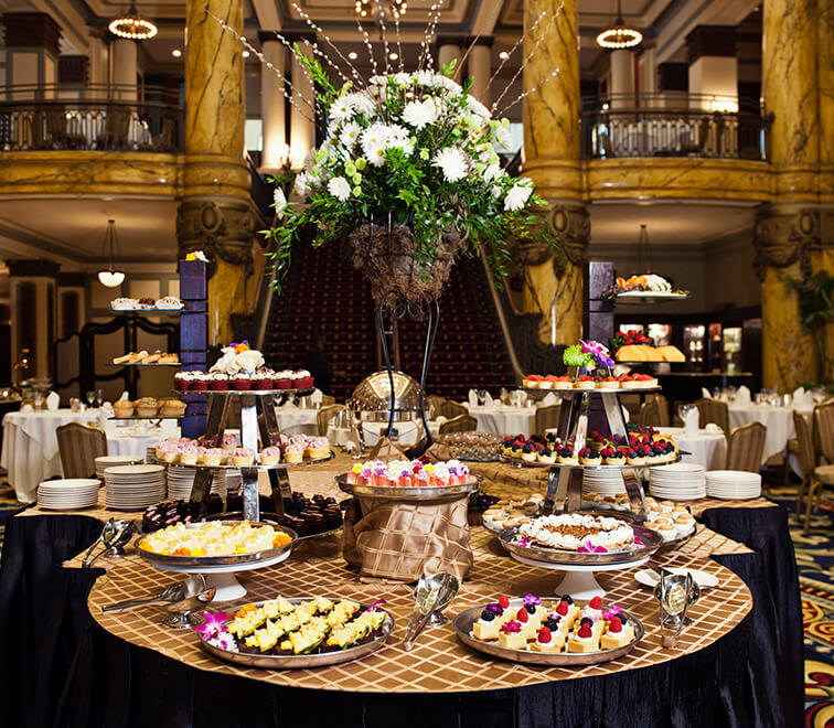 A large buffet table filled with various desserts and a floral arrangement in the center