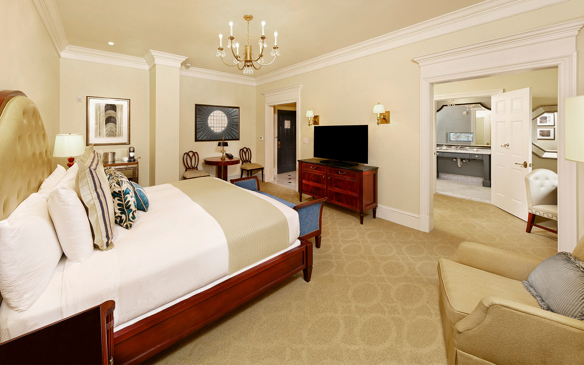 A wide view of a hotel room with a large bed, TV, and sitting area.