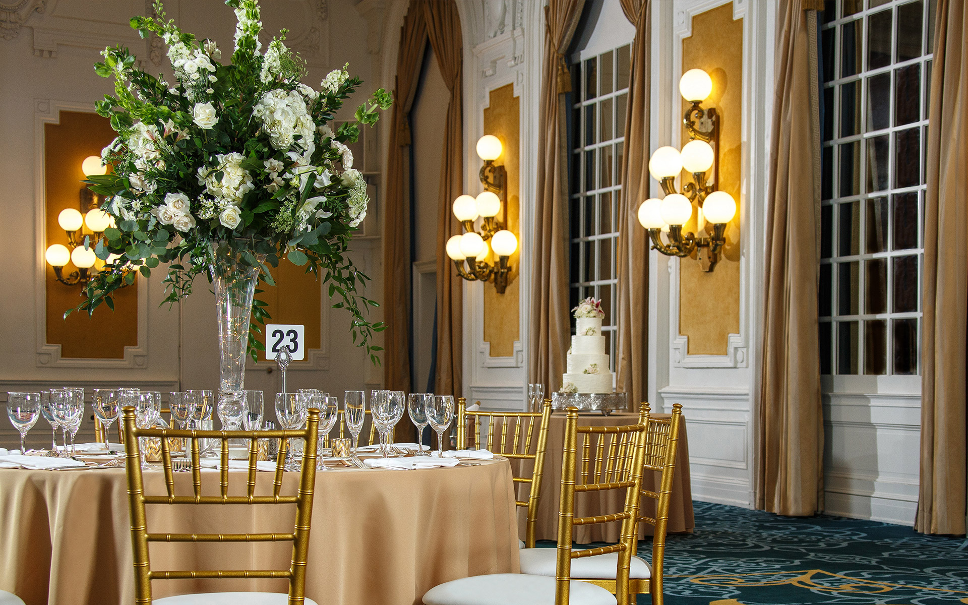 a dining table set for a special occasion with a floral centerpiece and a cake